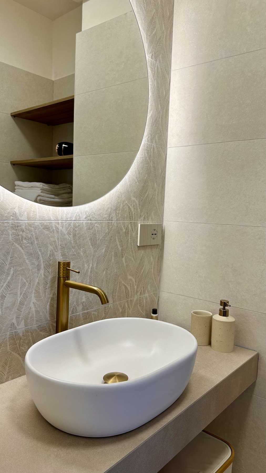 Il lavabo a bacinella con rubinetteria dorata e specchio retroilluminato