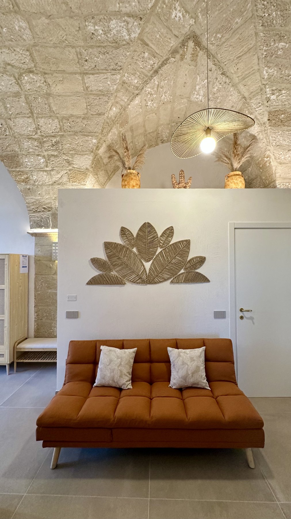 Il soggiorno con divano e decoro a parete in foglie di palma